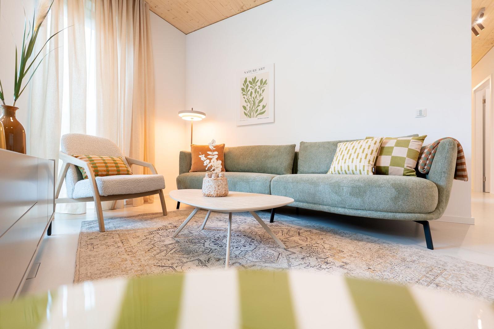 Ein Wohnzimmer mit Sofa, Sessel, Tisch und Teppich.
