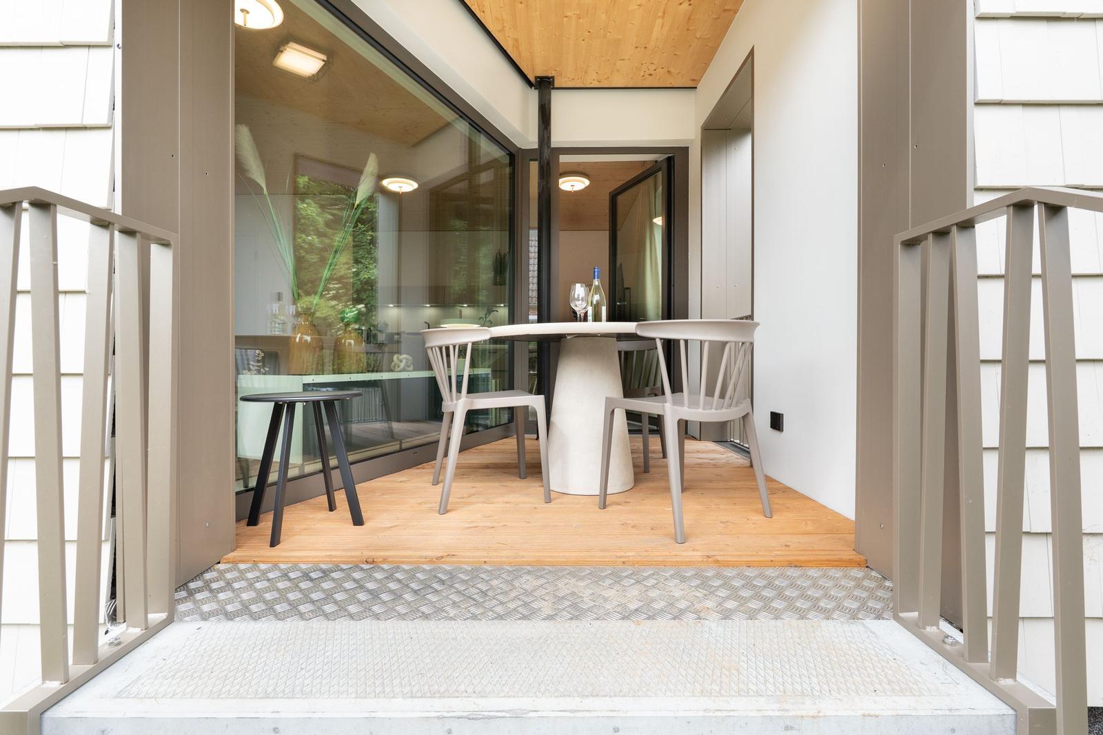 Terrasse mit Tisch und Stühlen, Blick in das Haus mit Holzdecke.