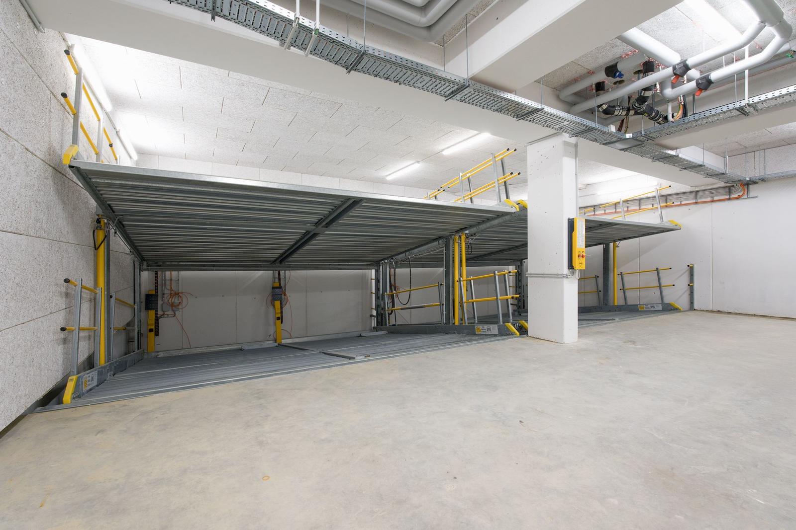 Automatisches Parkhaus mit mehreren Stellplätzen und gelben Sicherheitsgeländern.