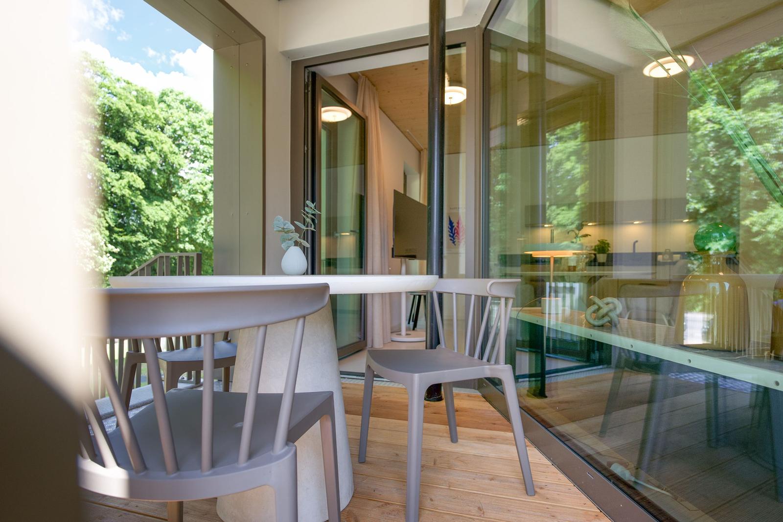 Terrasse mit Tisch und Stühlen, Blick ins Innere mit Küche und Wohnbereich.
