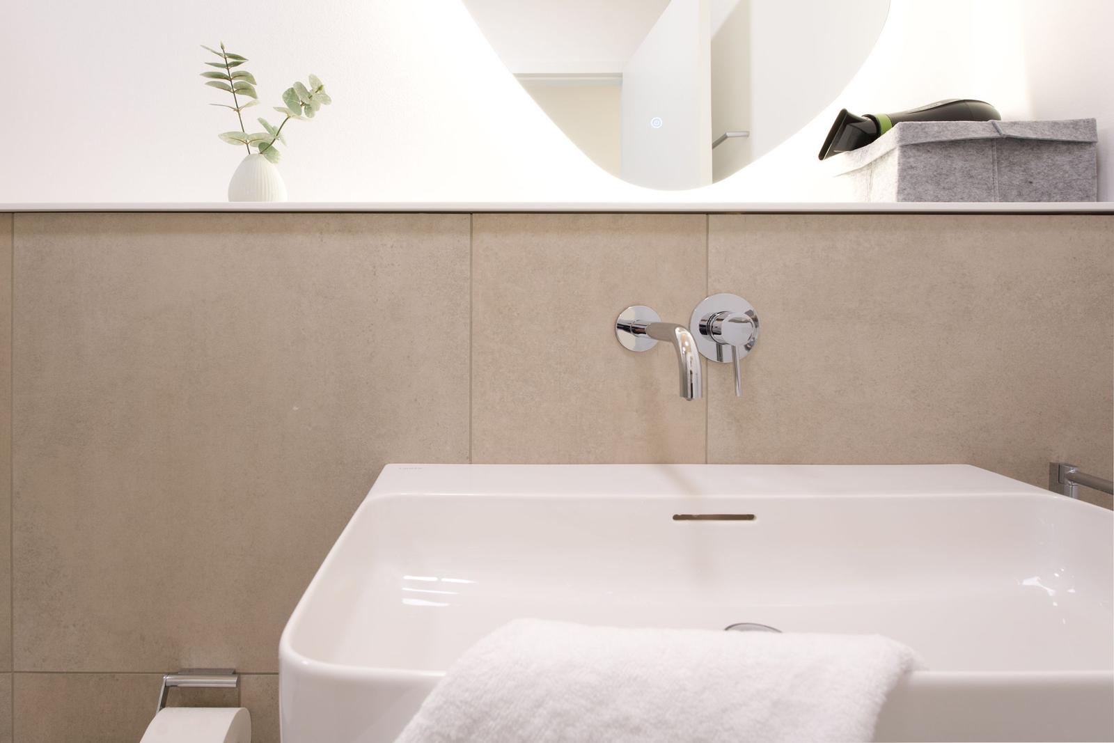 Waschbecken mit Wasserhahn, Spiegelfläche und Handtuch