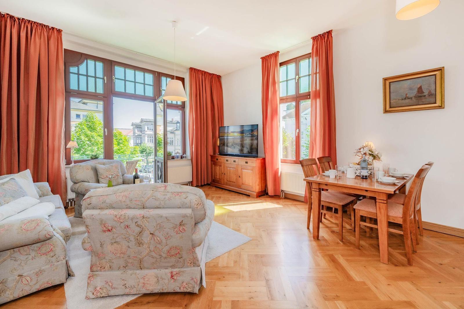 Wohn- und Essbereich mit Holzboden, Sofa, Esstisch und TV.