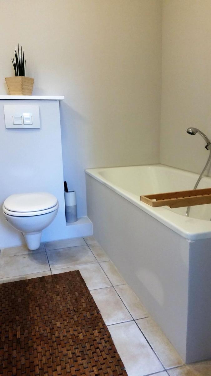 Badezimmer mit Badewanne, Toilette und Badezimmerteppich.