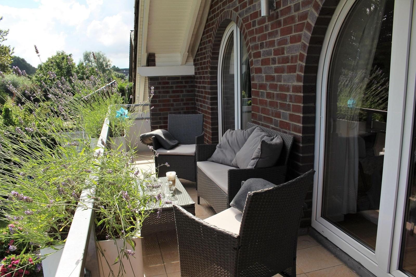 Terrasse mit Sitzgruppe, Pflanzen und Blick auf Grünflächen.