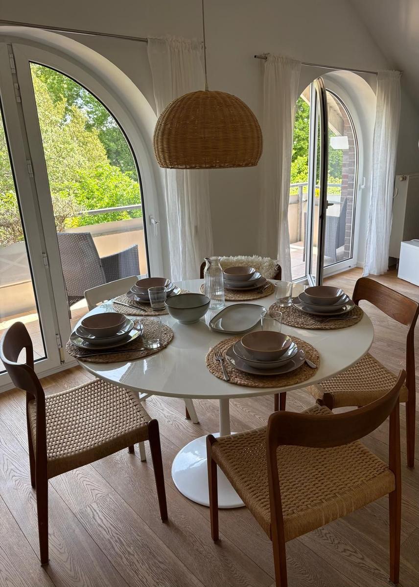 Runder Tisch mit Stühlen, Platz für sechs Personen, Blick auf Balkon mit Grün.