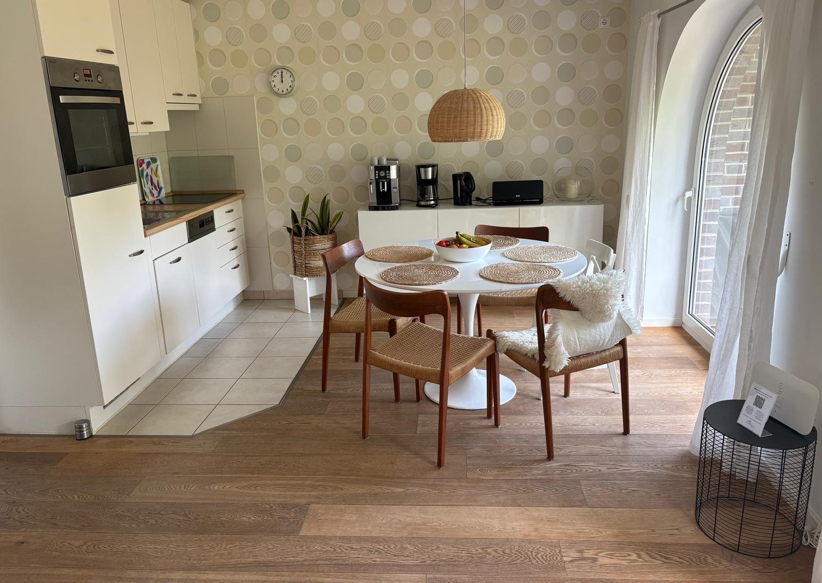 Küche und Essbereich mit runden Tisch, Holzstühlen und Wand mit runden Mustern.