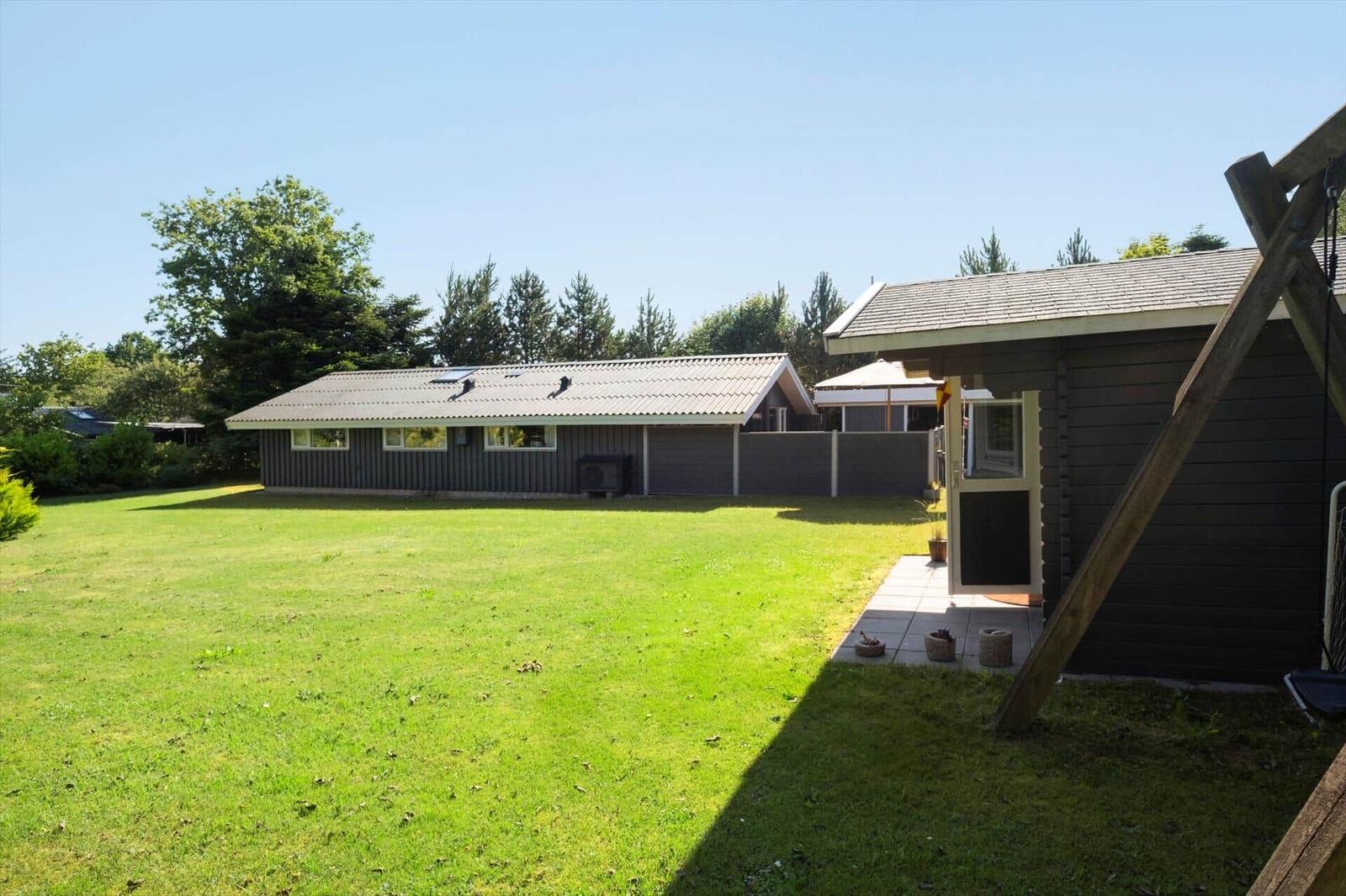 Ein Haus mit großem Garten und Terrasse unter klarem Himmel.