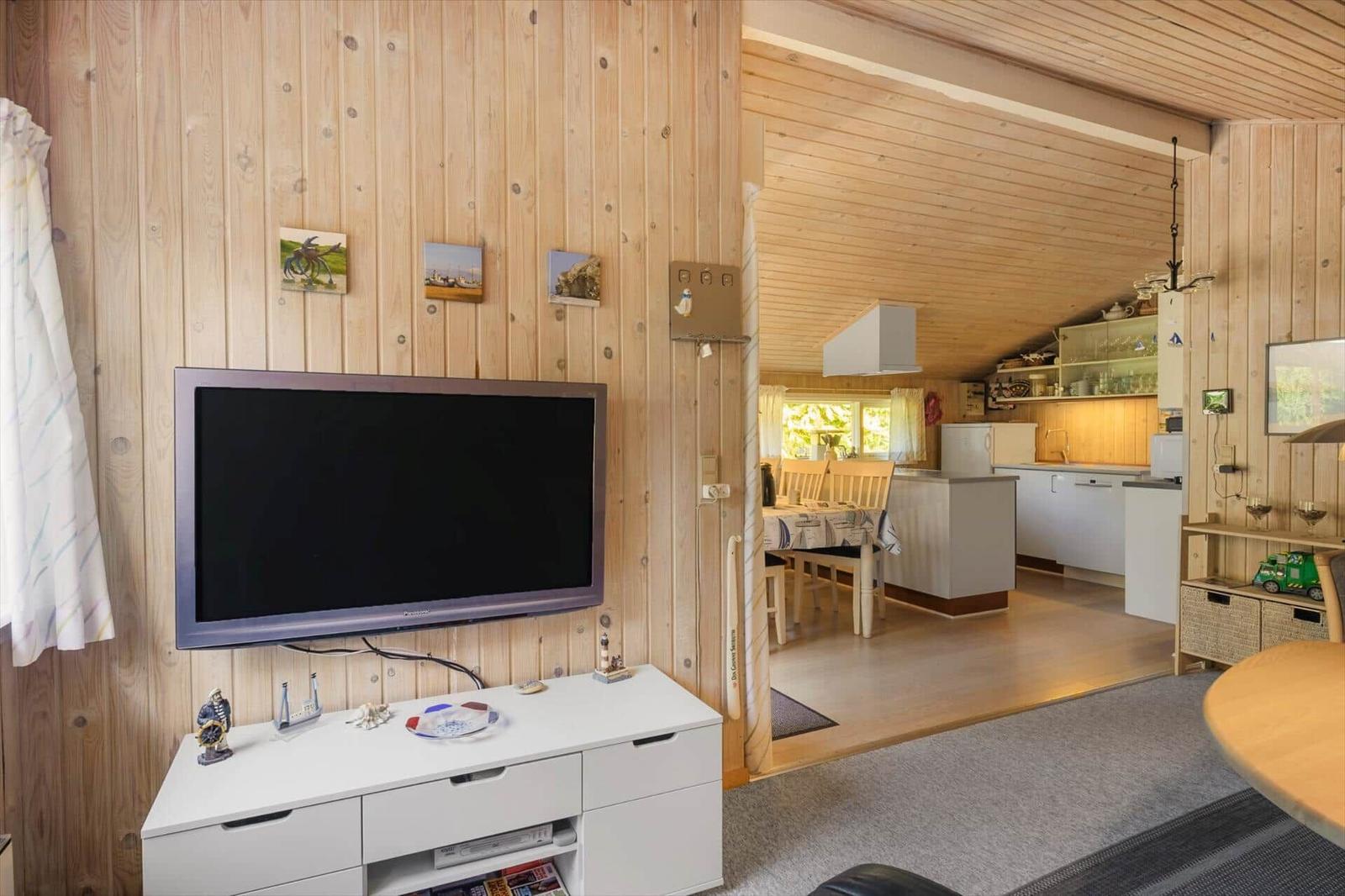 Wohnbereich mit Fernseher und Küche im Hintergrund