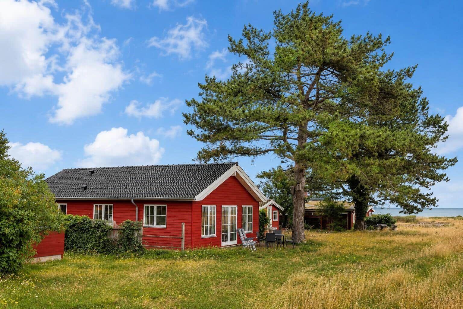 Rotes Haus mit Garten und Blick aufs Meer unter blauem Himmel.