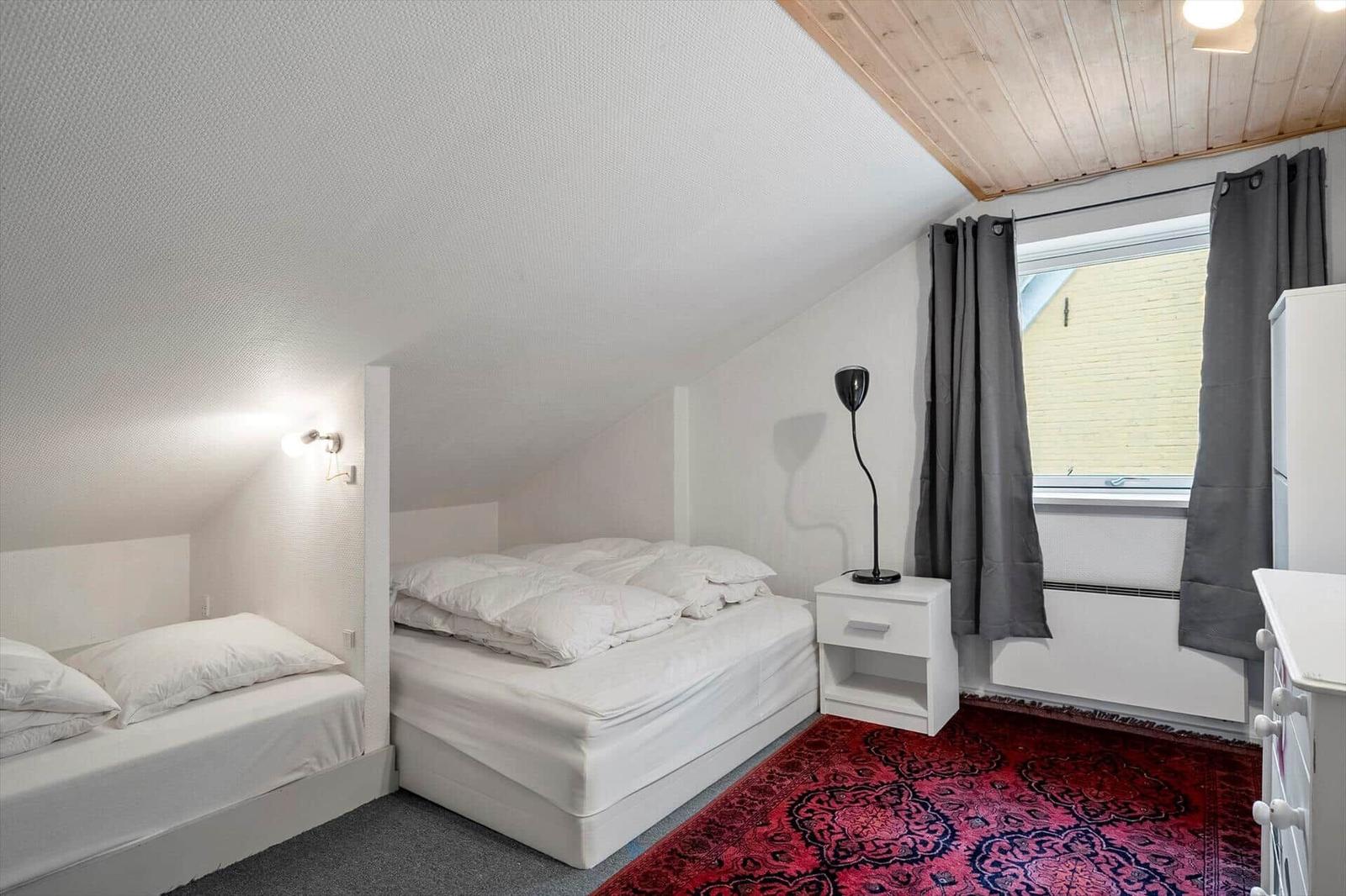 Zimmer mit zwei Betten, rotem Teppich und Holzdecke.