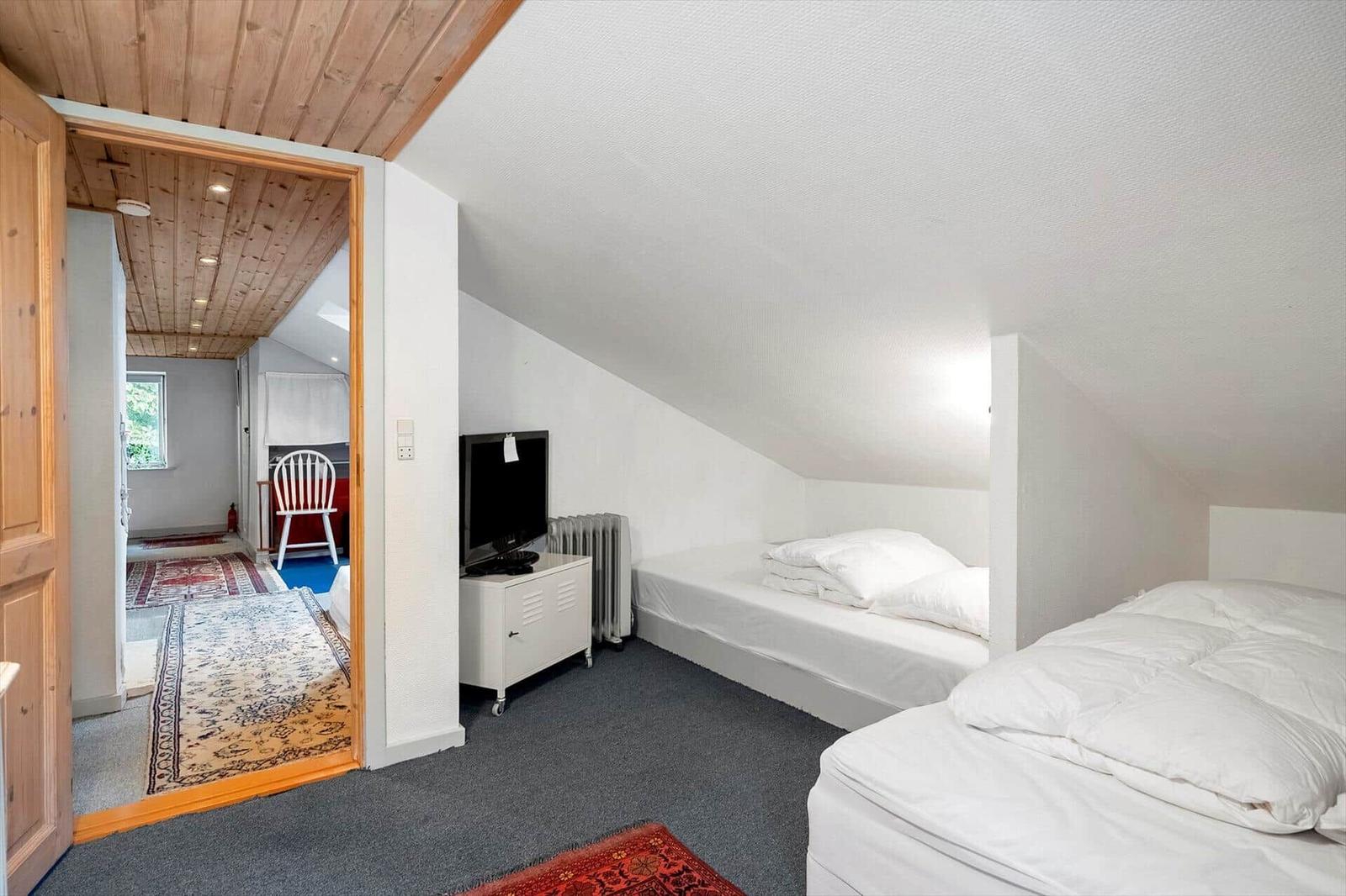 Zimmer mit zwei Betten, Fernseher und Sicht auf angrenzendes Zimmer.