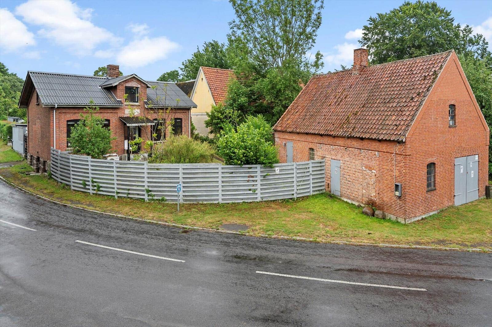Zwei Backsteinhäuser mit Dach und Zaun an einer Straße