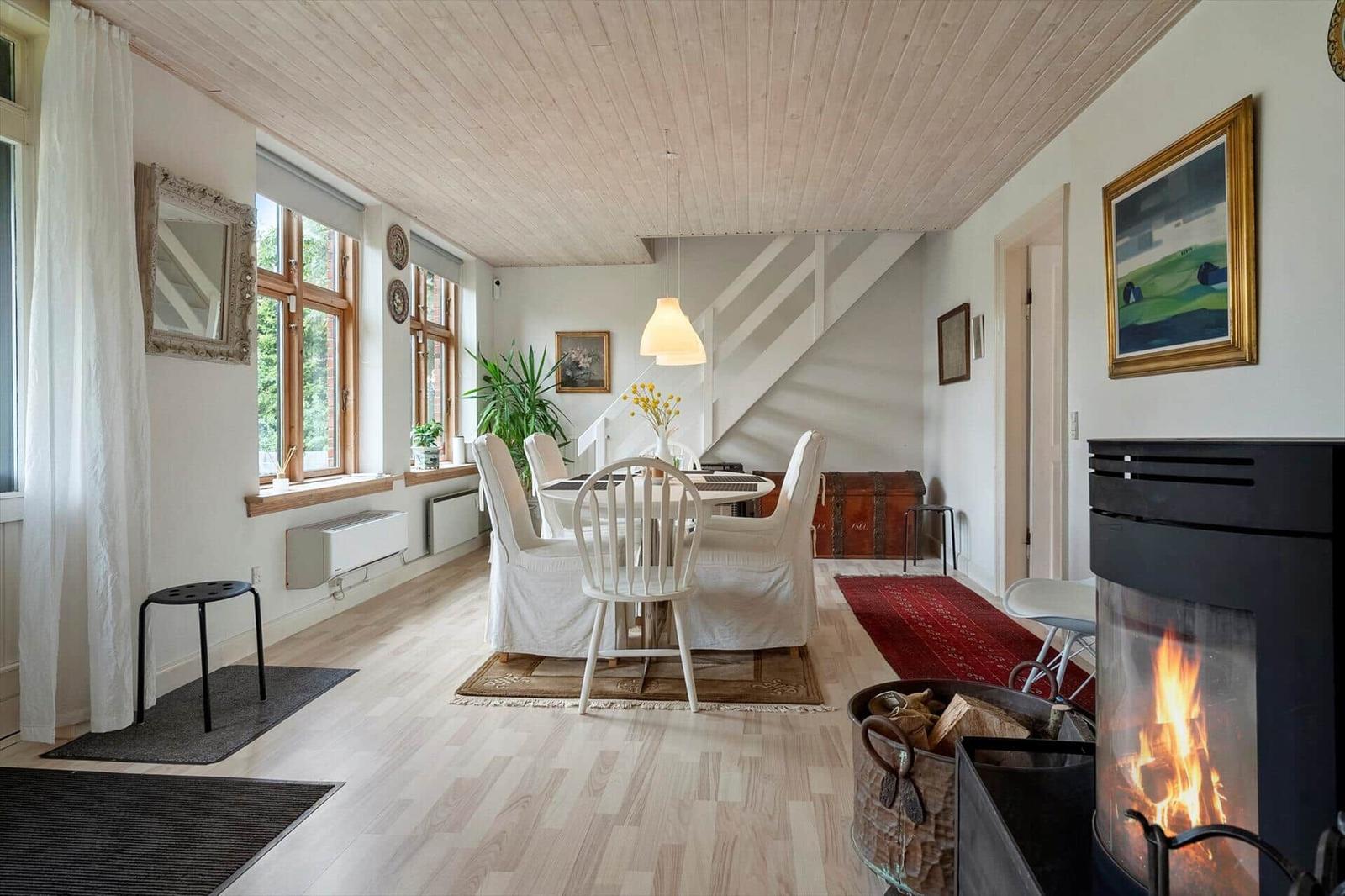 Ein Esszimmer mit Holzboden, einem Kamin und einer Treppe im Hintergrund.