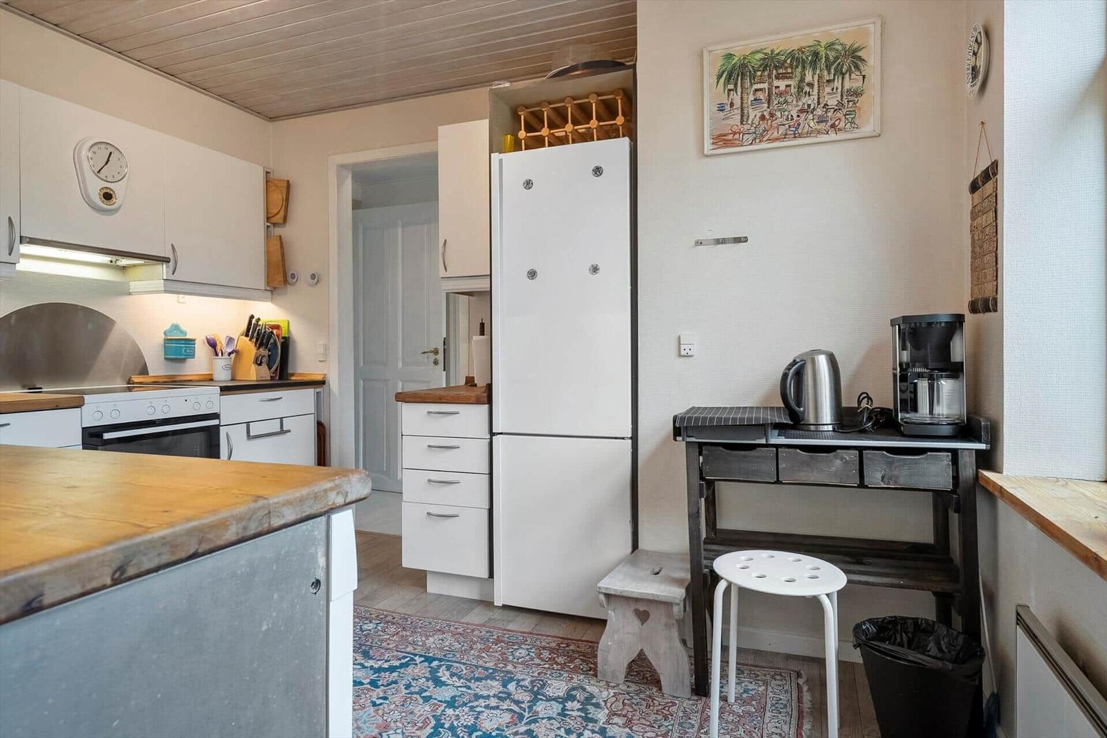 Küche mit weißer Kühlschrank, Holzoberflächen und Küchenspüle.