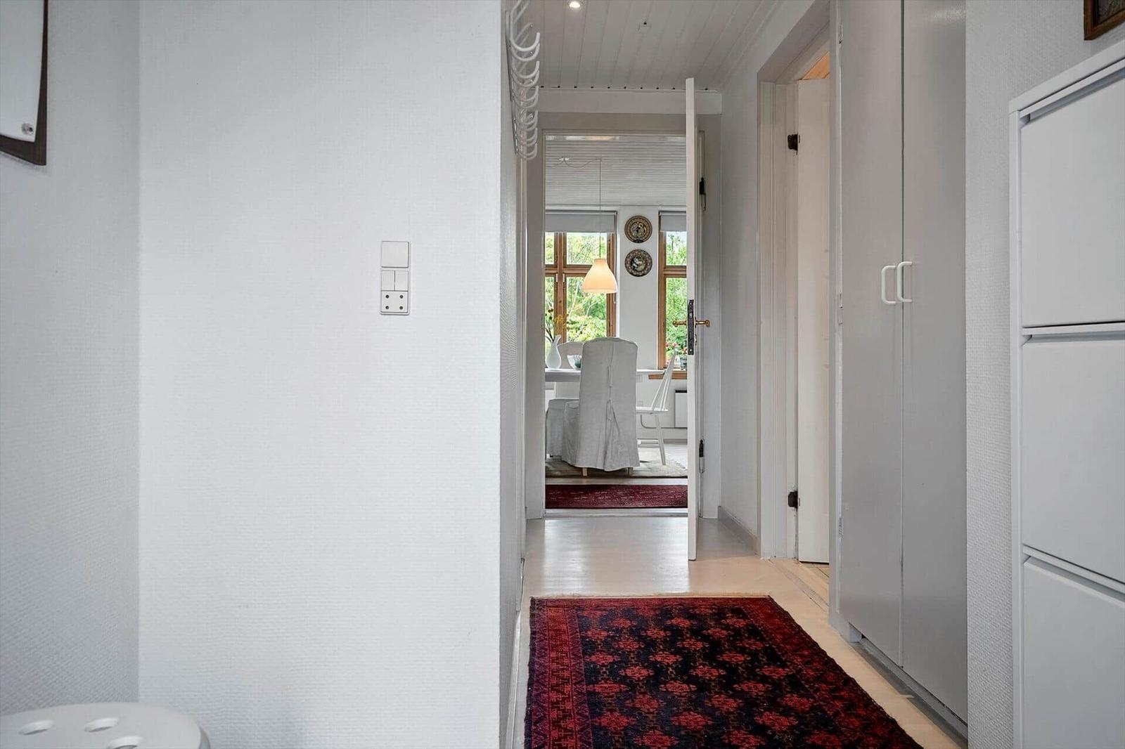 Flur mit Teppich, Schrank und Blick in Esszimmer mit Tisch und Stühlen.
