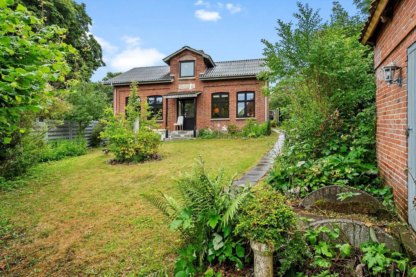Rotes Backsteinhaus mit Garten und Weg zur Eingangstür.