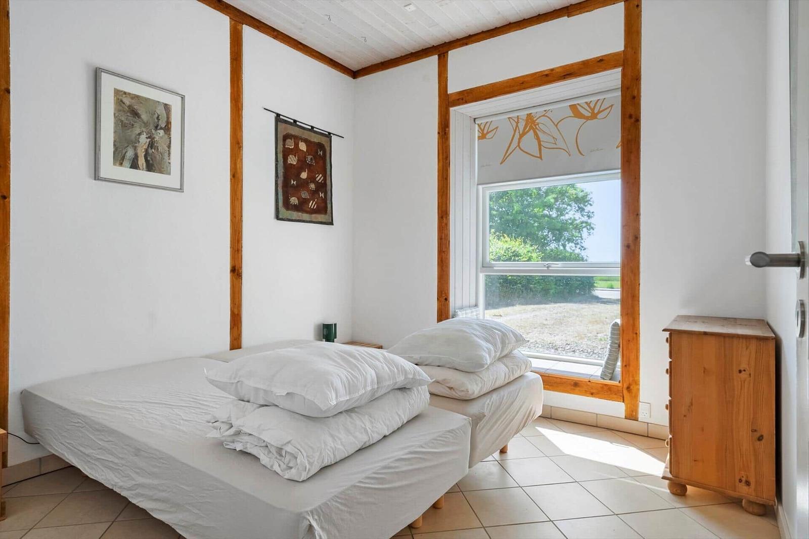 Bedroom with bed, window, and wooden furniture.