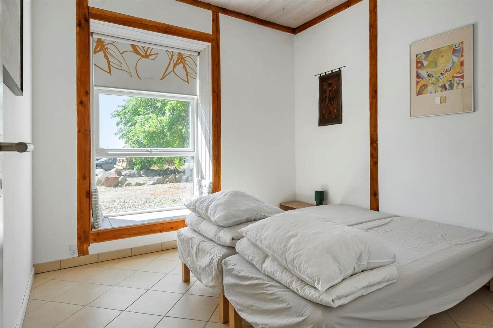 Bedroom with double bed, window, and artworks on the walls.