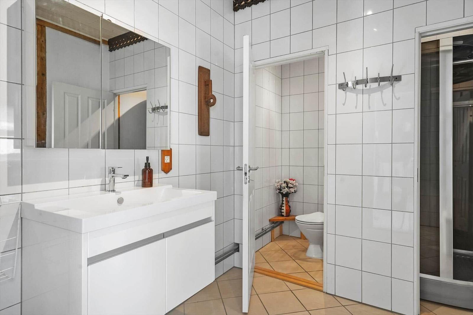 Bathroom with sink, mirror, and toilet in the adjoining room.