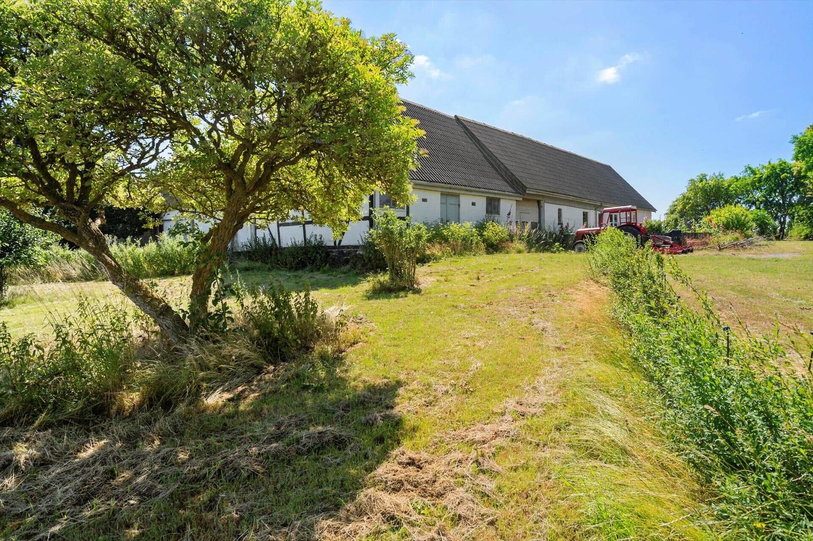 House with roof and garden, red tractor parked beside it.