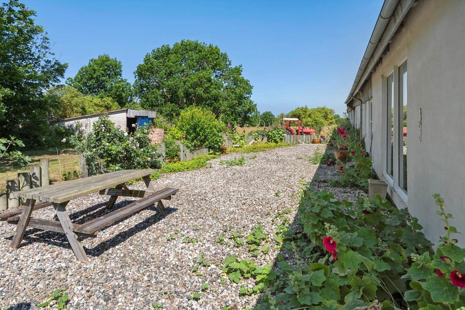 Garden with picnic table, flower beds, and gravel path beside house wall.