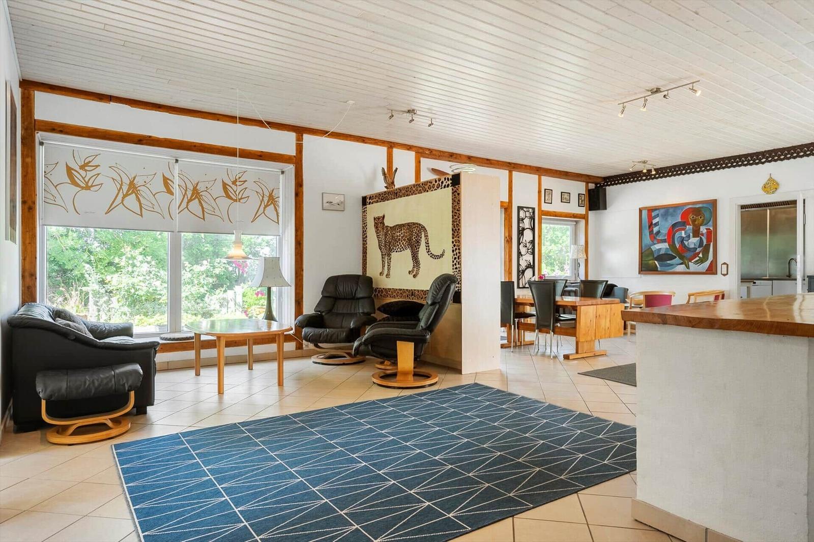 Living and dining area with seating, table, rug, and windows to the outside.