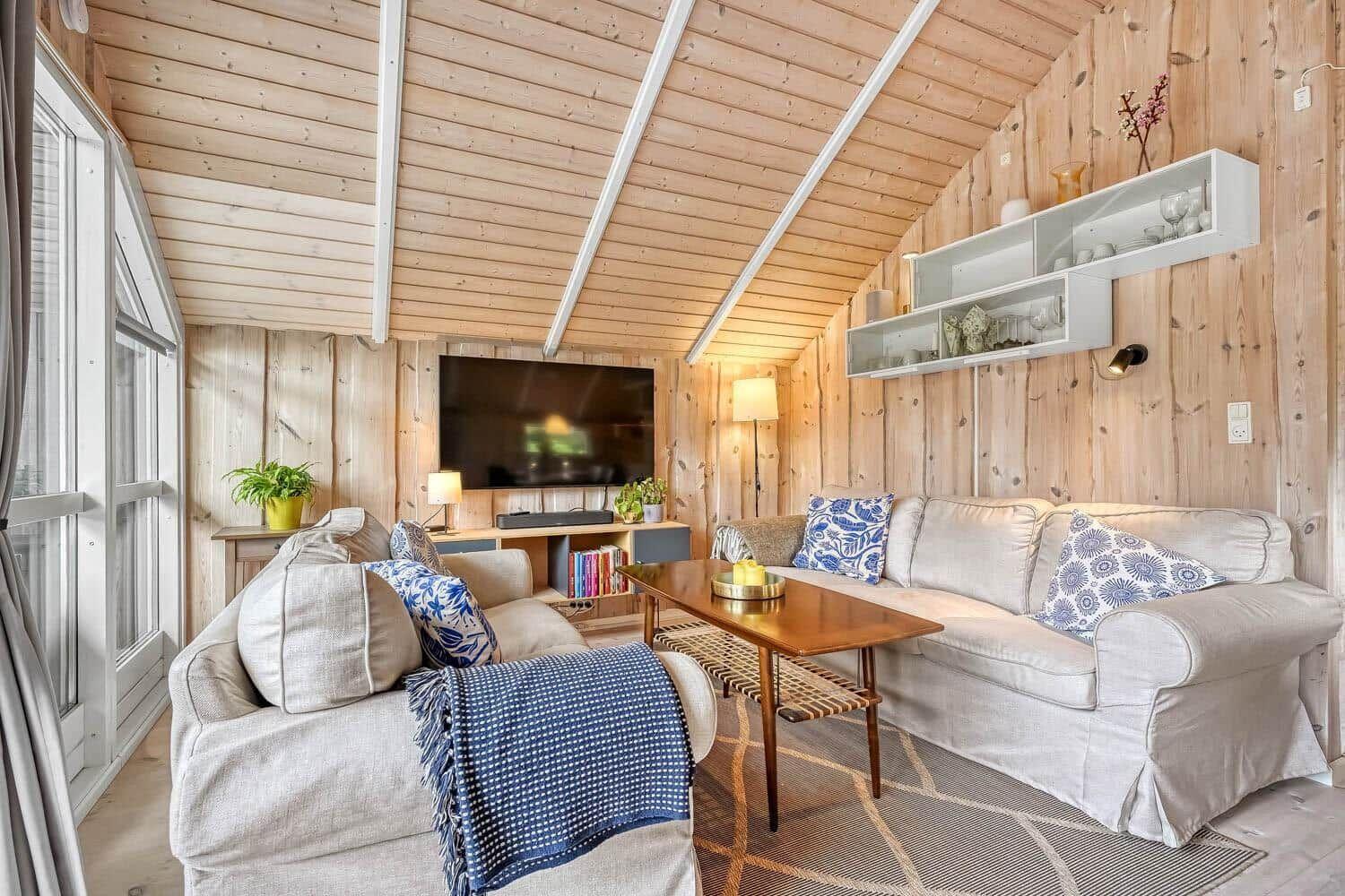 Wohnzimmer mit Holzwand, Sofa, Fernseher und Tisch