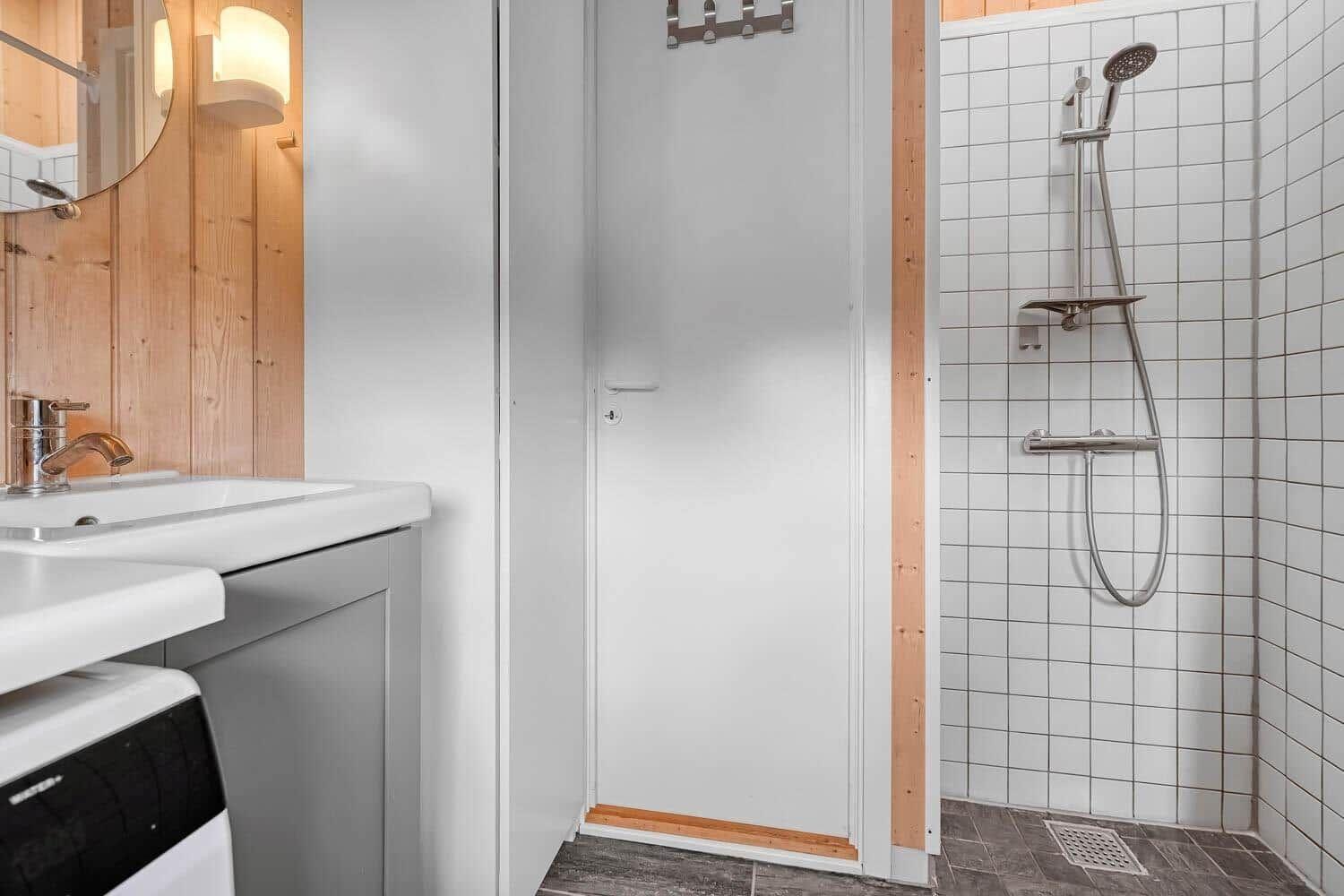 Badezimmer mit Dusche, Waschbecken und Spiegel an Holzwand