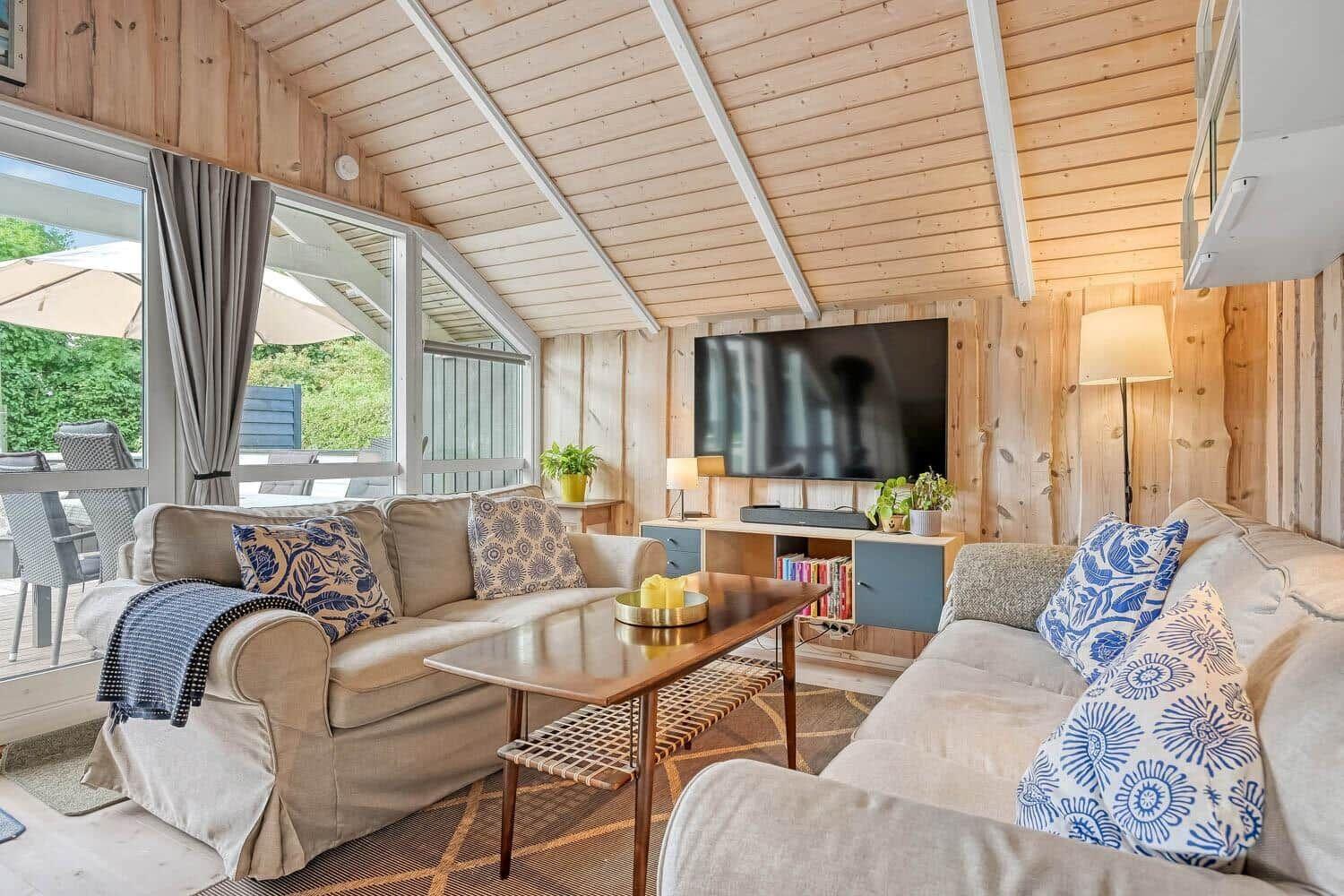 Wohnzimmer mit zwei Sofas, Fernseher und Blick auf die Terrasse.