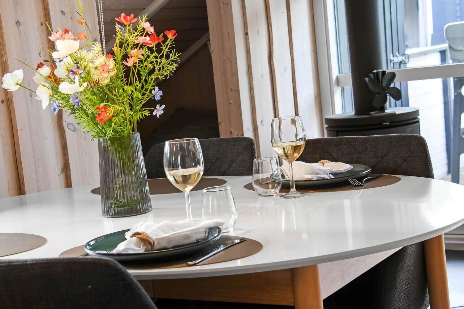 Runde Tisch mit Platz für zwei, Blumenvase und Weingläser.