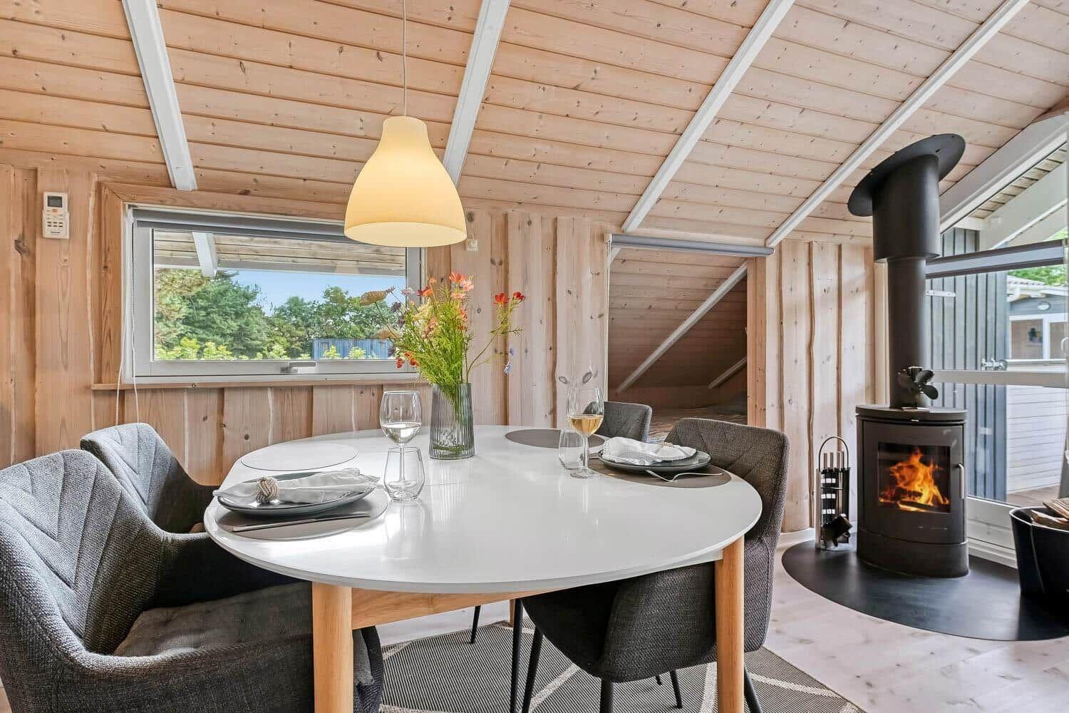 Rundtisch mit Stühlen, Kamin und Fenster mit Blick auf Grün.
