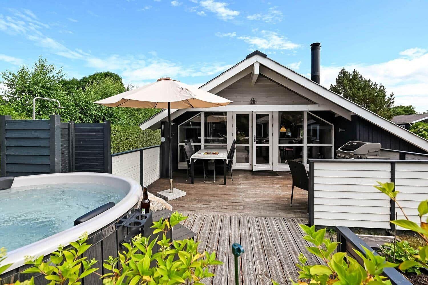 Haus mit Terrasse, Whirlpool und Grillplatz im Freien.