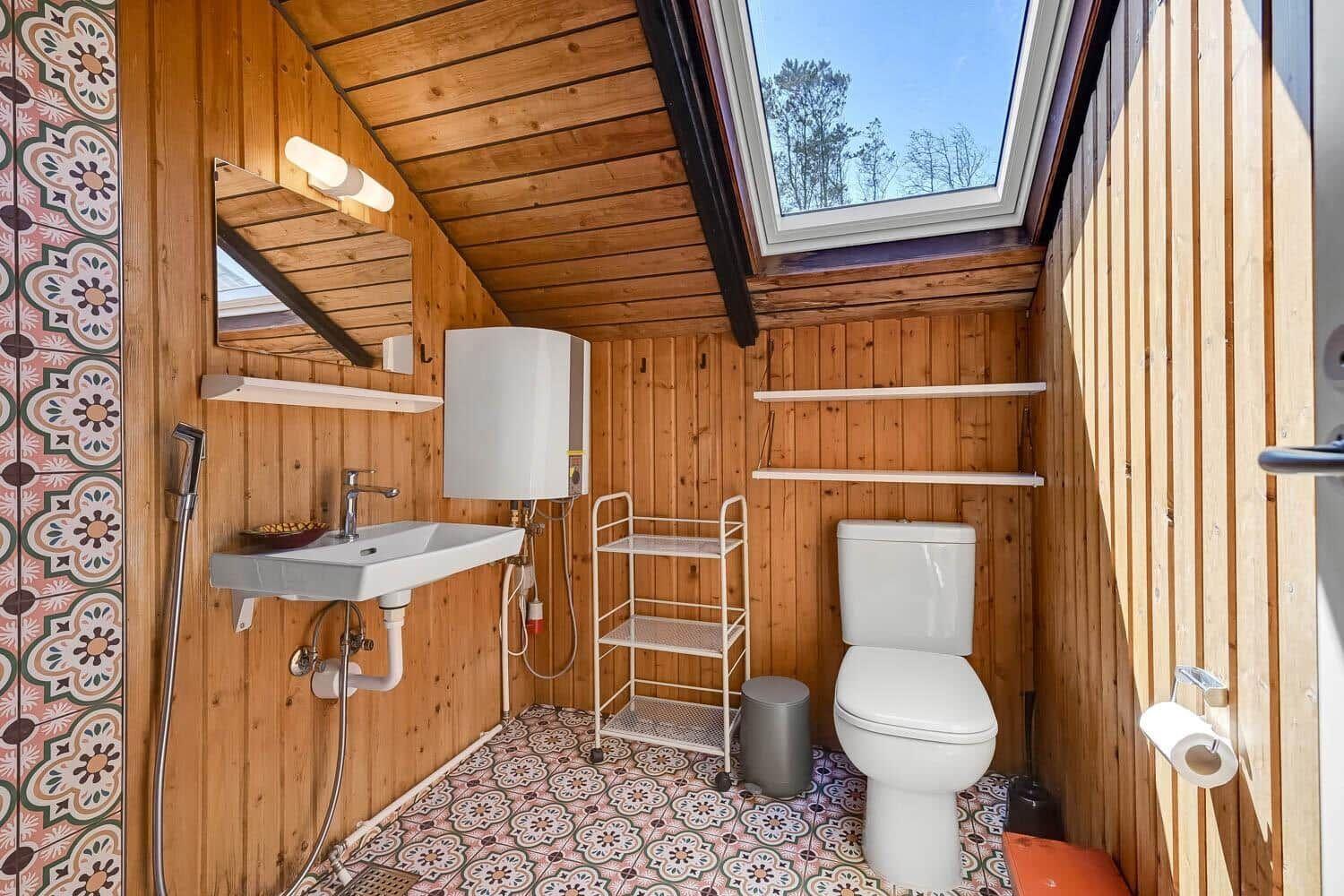 Badezimmer mit Holzwand, Duschwanne, Toilette und Dachfenster