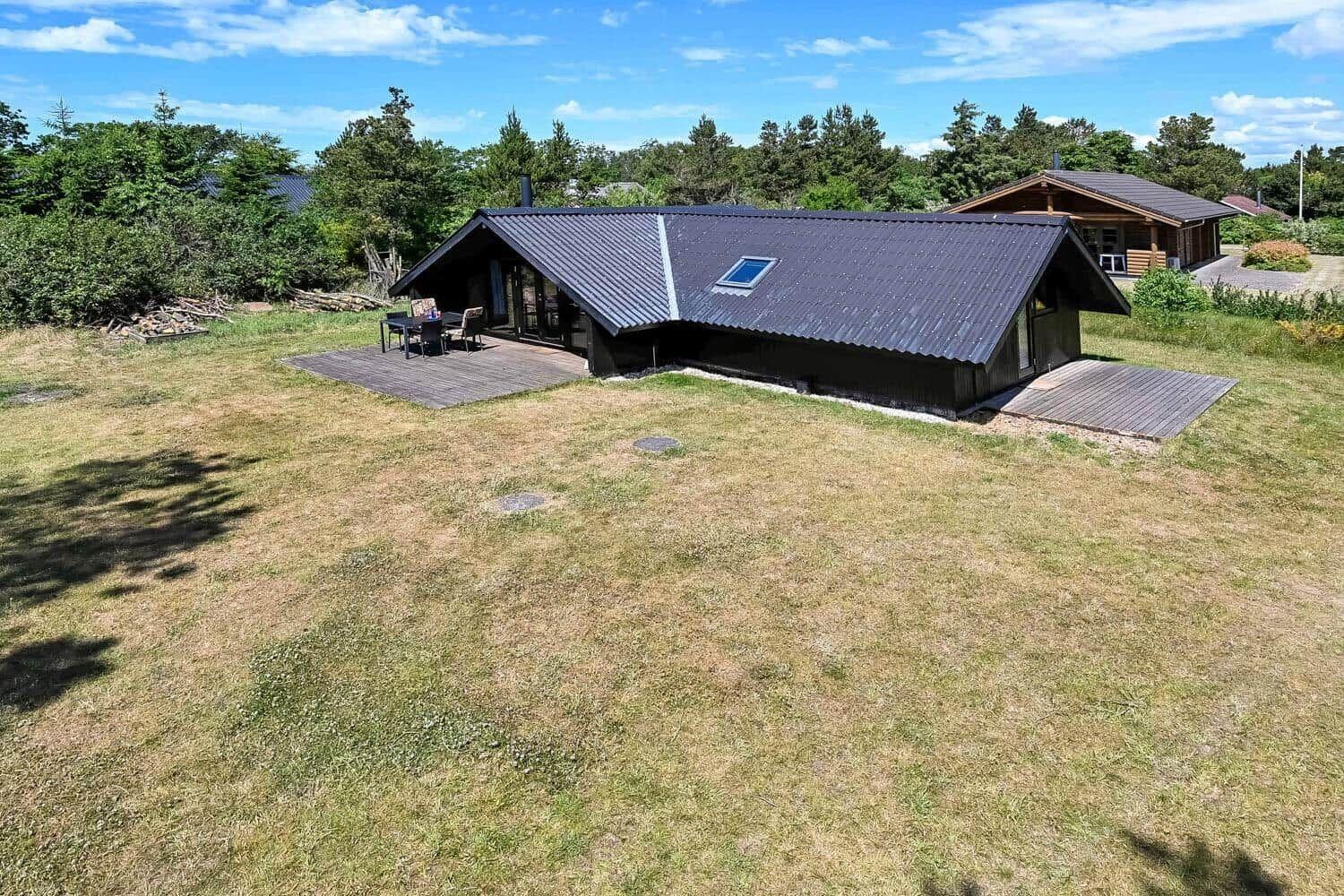 Moderne Holzhütte mit Terrasse und Garten. Blick auf das Haus mit Dach und Umgebung.