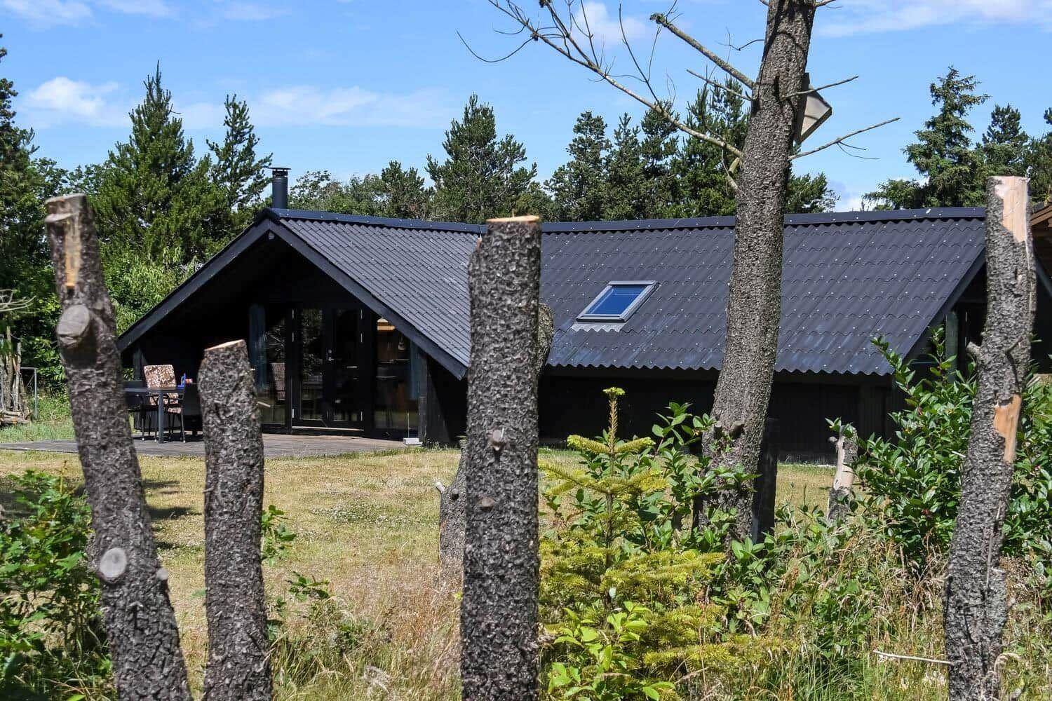 Holzhaus mit Dachgaube und Terrasse im Wald. Blick durch Stumpfe.