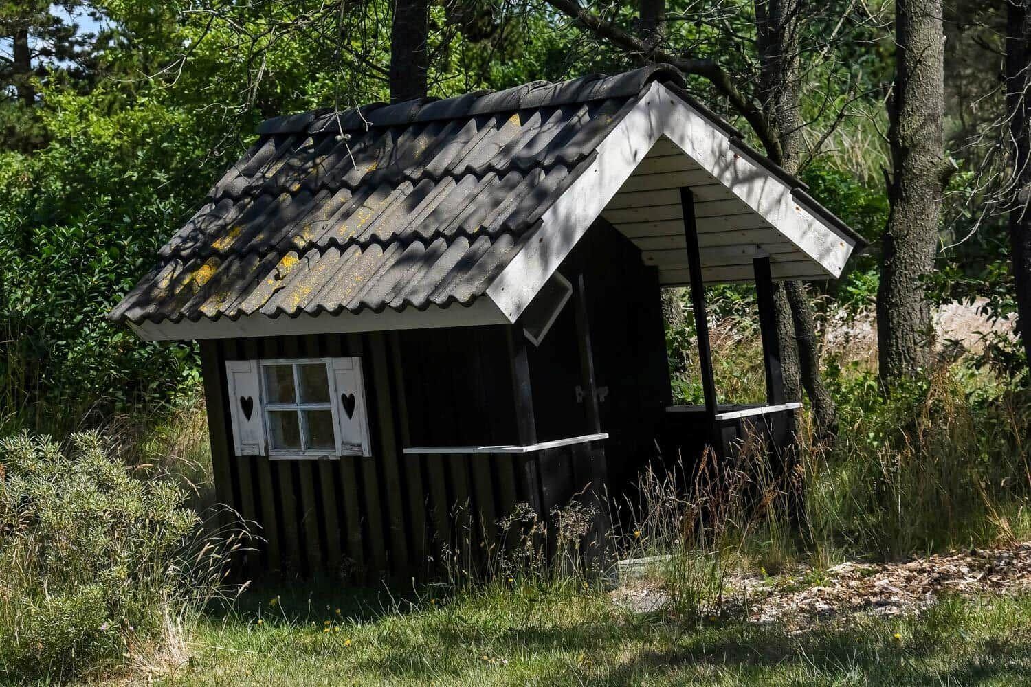 Ein kleines Holzhaus mit Dach und Fenster im Wald