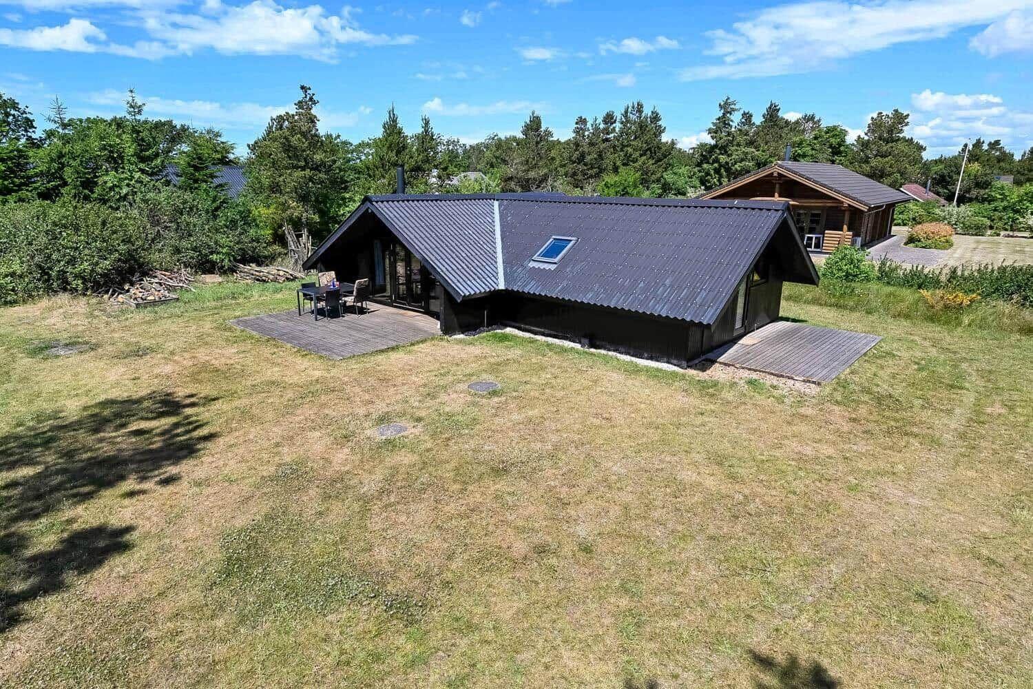 Moderne Holzhütte mit Terrasse und Garten. Blick auf das Haus und die Umgebung.