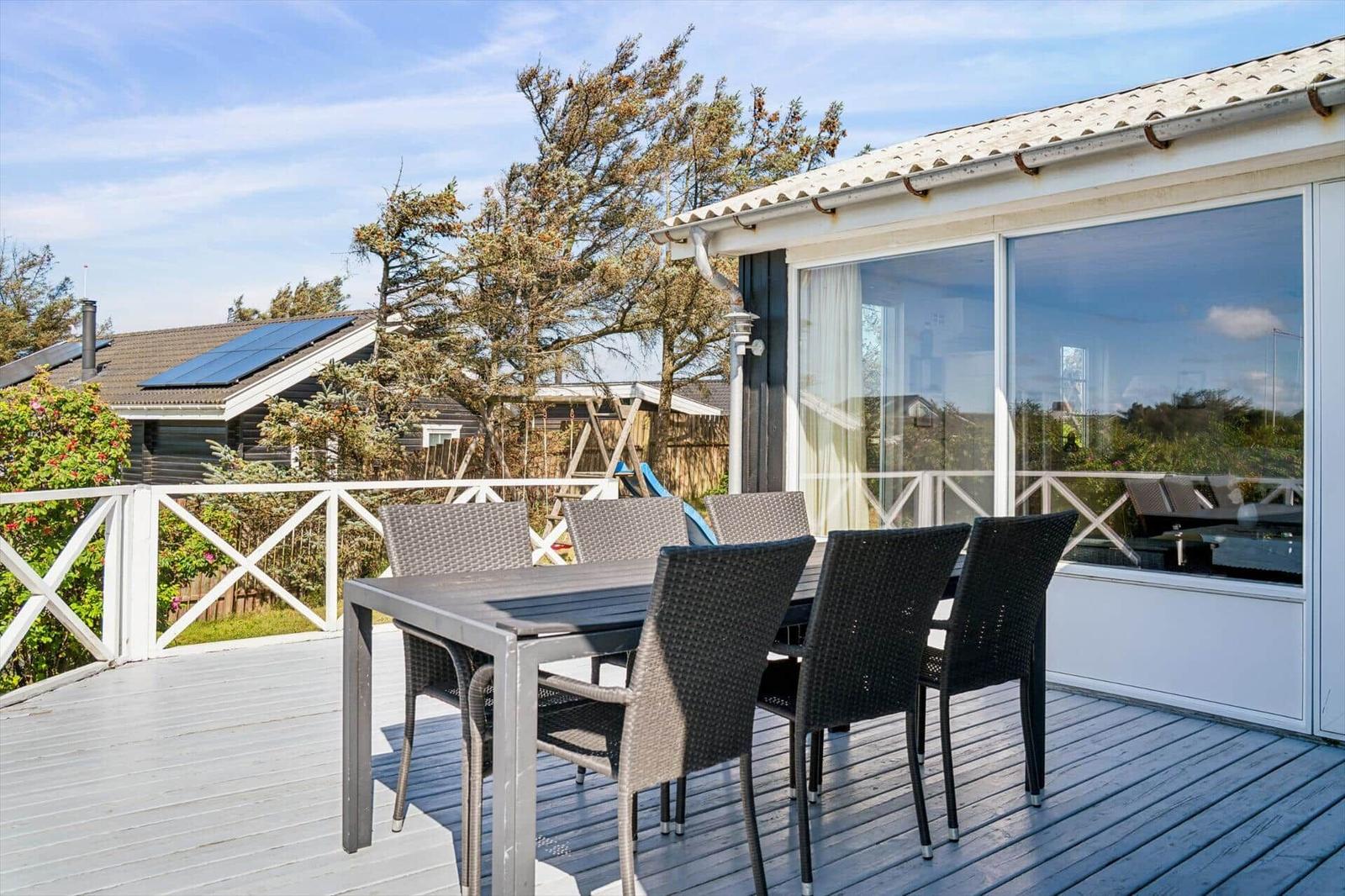 Terrasse mit Tisch und Stühlen, Blick auf Garten und Nachbarhaus.