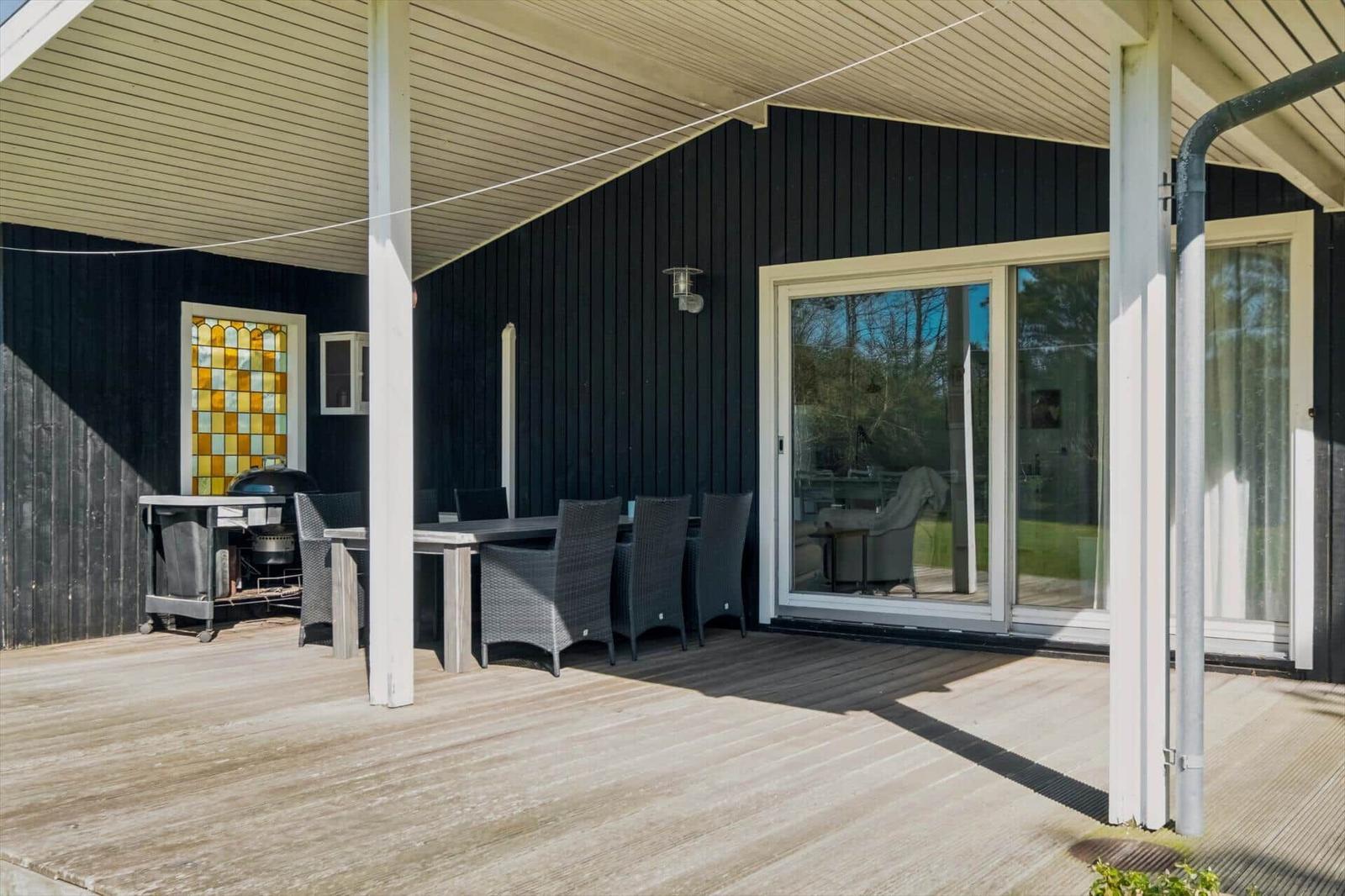 Deck with table, chairs, and grill under roof