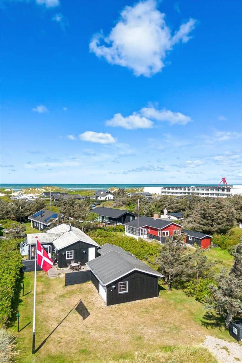 Schwarze und rote Häuser mit Flagge, Strand und Hotel im Hintergrund.