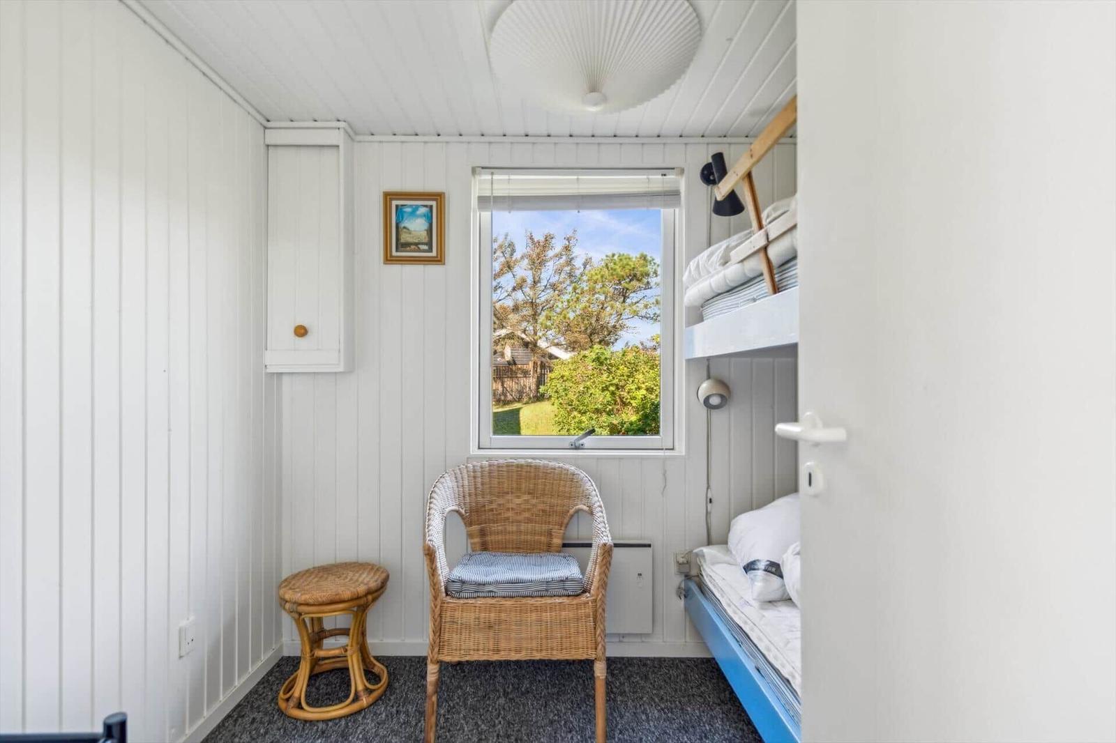Ein Raum mit Doppelstockbett, Stuhl und Fenster mit Blick auf Grün.