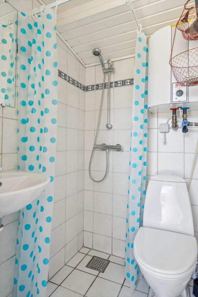 Badezimmer mit Dusche, Toilette und Waschbecken. Duschvorhang mit blauen Punkten.