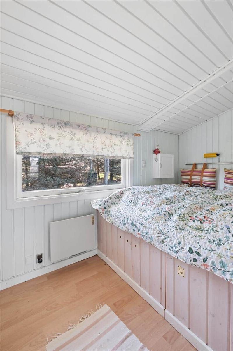 Bedroom with bed, window, and heater on the wall.