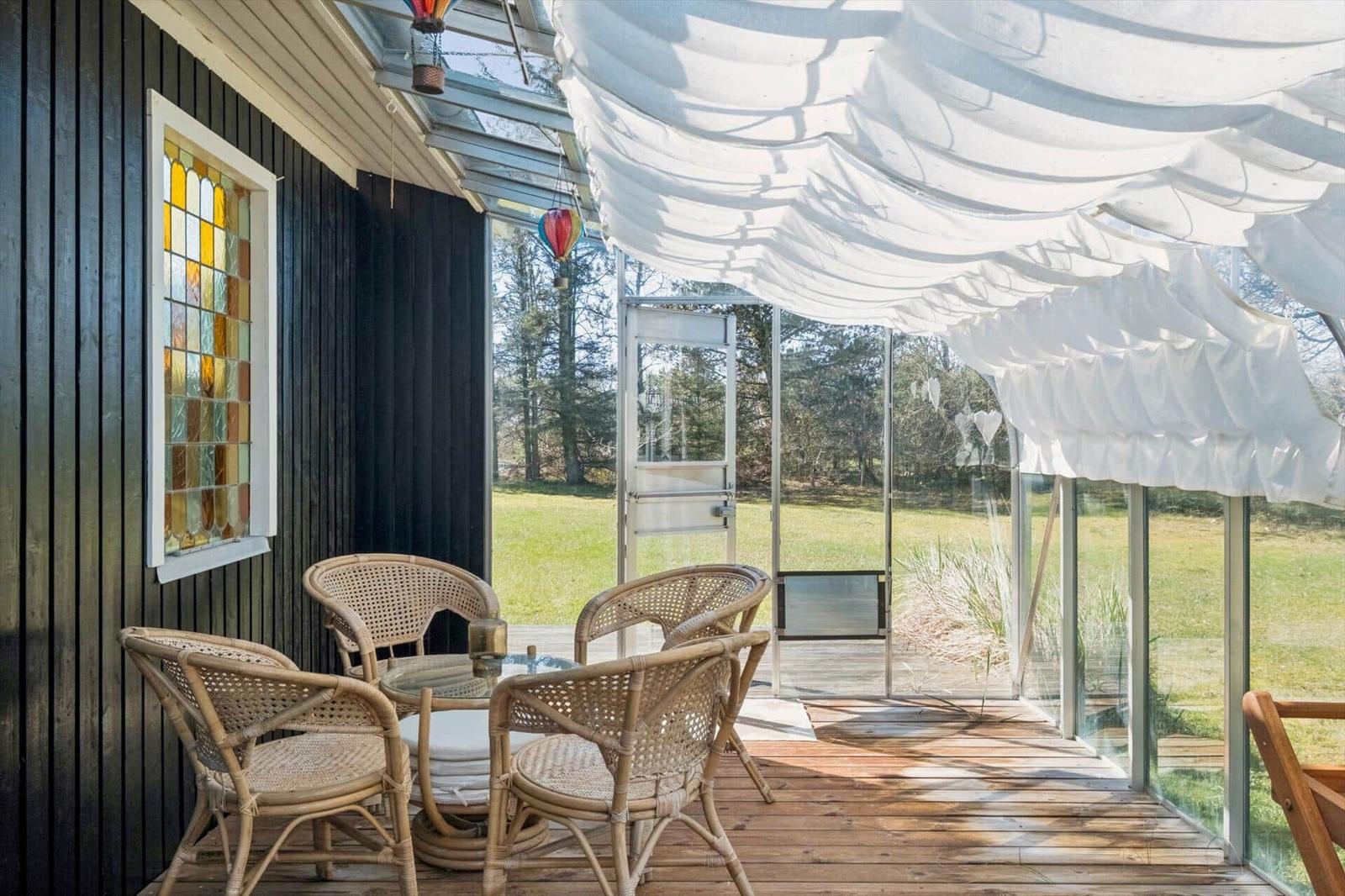 Terrace with rattan furniture, glass front, and colorful window.