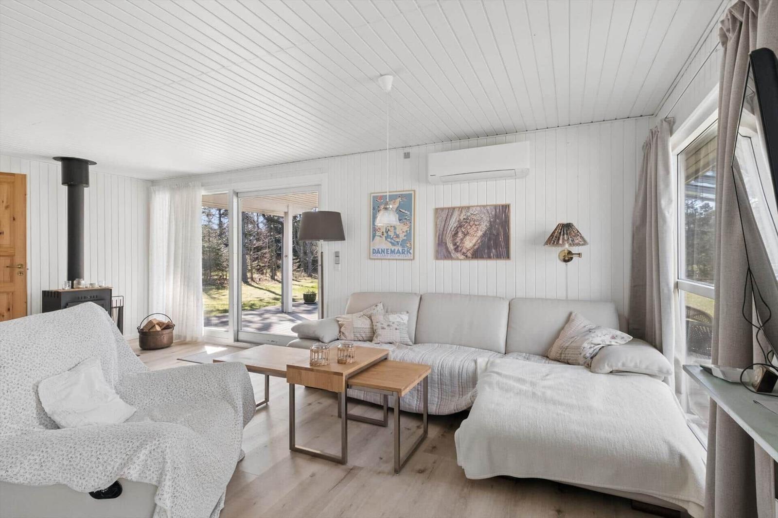 Living room with sofa, coffee table, and wooden floor. Windows overlook the garden.