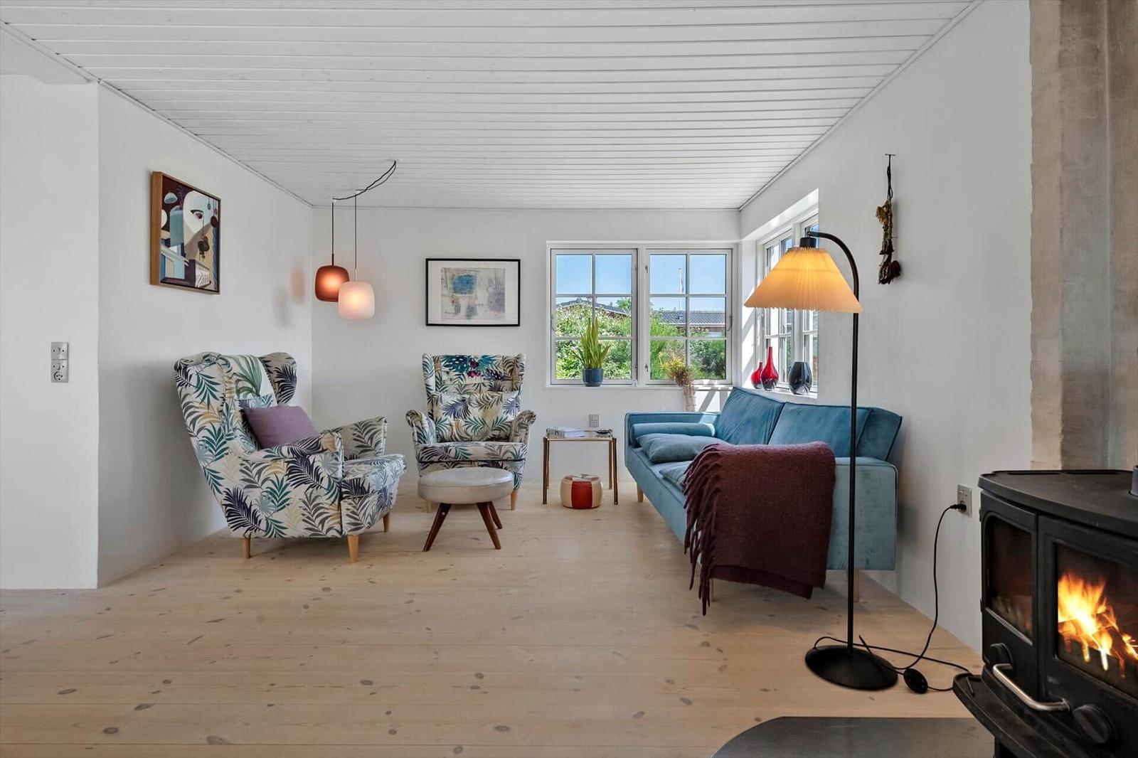 Living room with sofa, two chairs, fireplace, and windows with view.