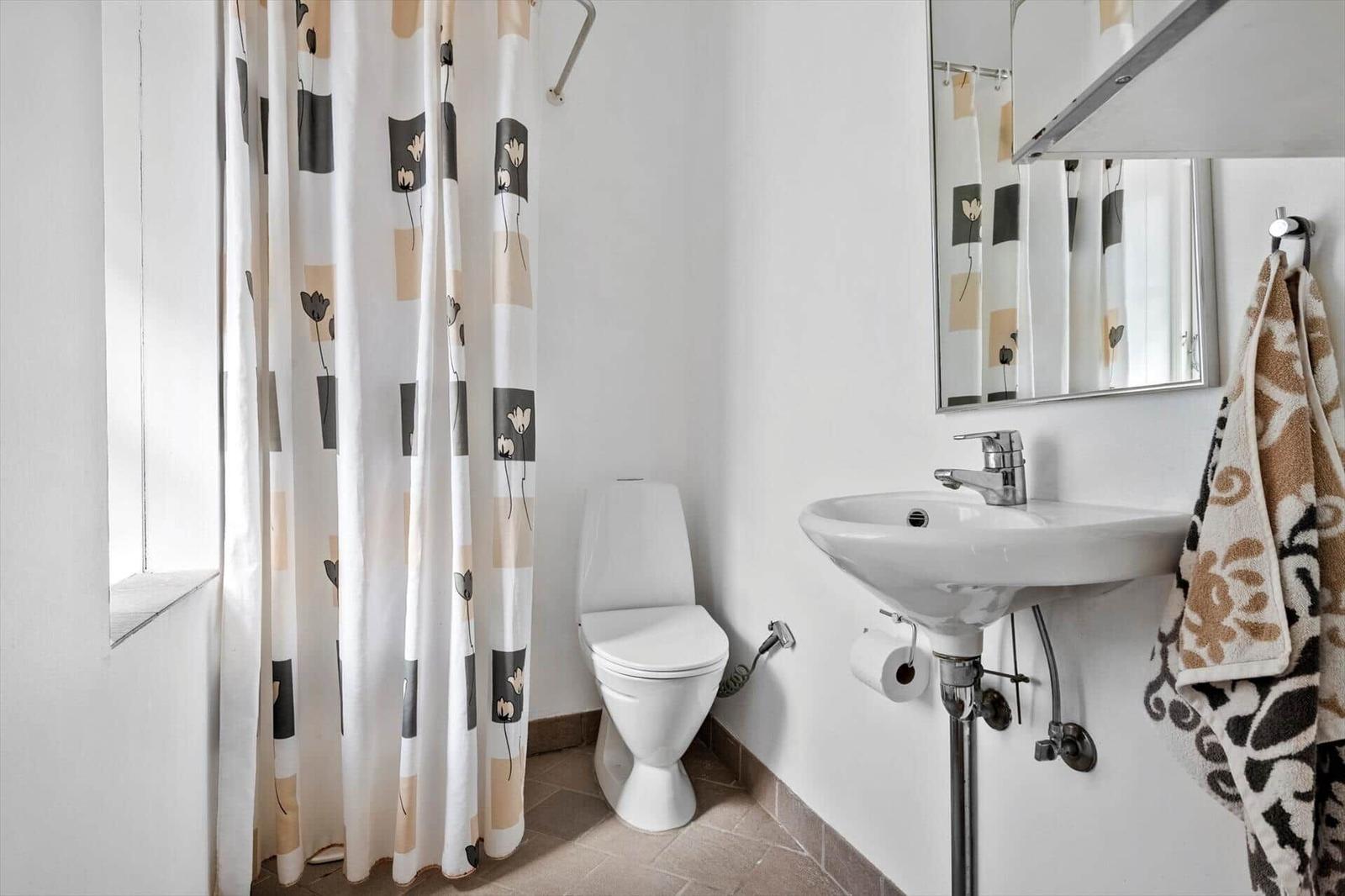 Bathroom with toilet, sink, and shower curtain with pattern.