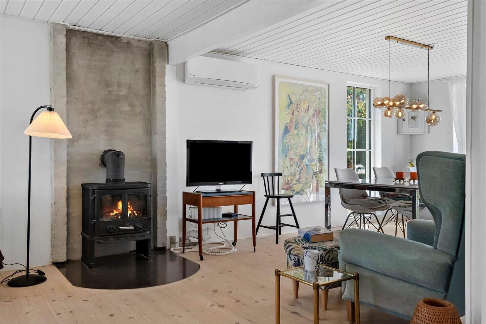 Living and dining area with fireplace, TV, and modern lighting.