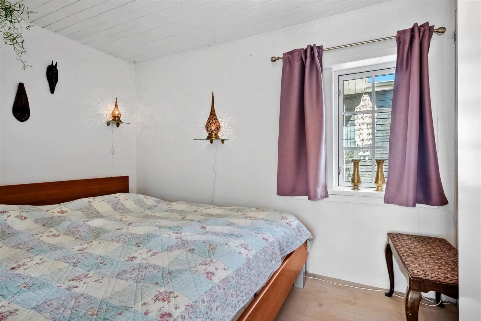 Bedroom with bed, window, curtains, and wall lamps.