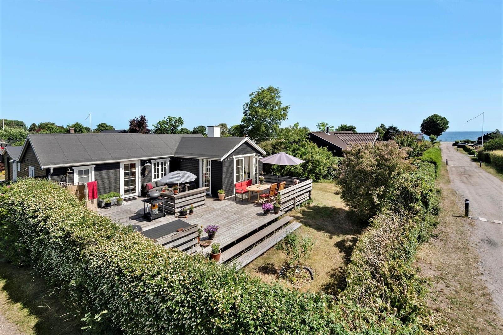 Wooden house with large deck, garden, and sea view.